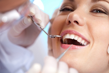 smiling patient with dental pick and mirror in front of face