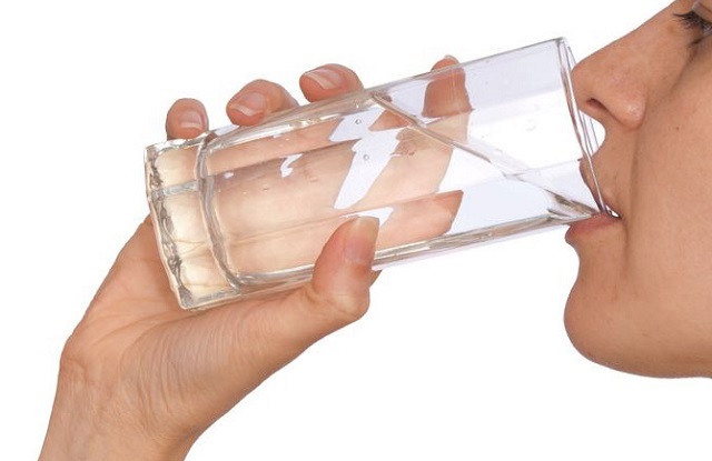 woman drinking water out of glass