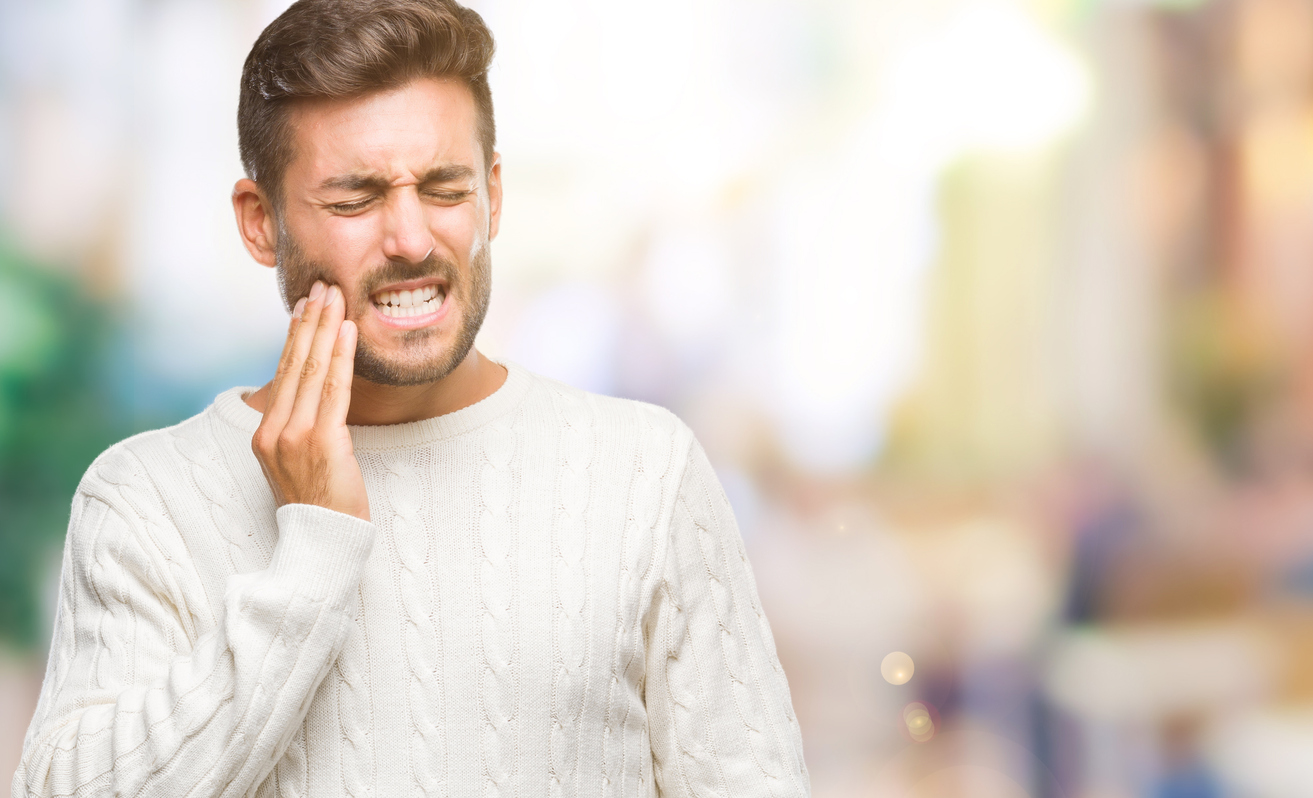Young handsome man wearing winter sweater over isolated background touching mouth with hand with painful expression because of toothache or dental illness on teeth. Dentist concept.