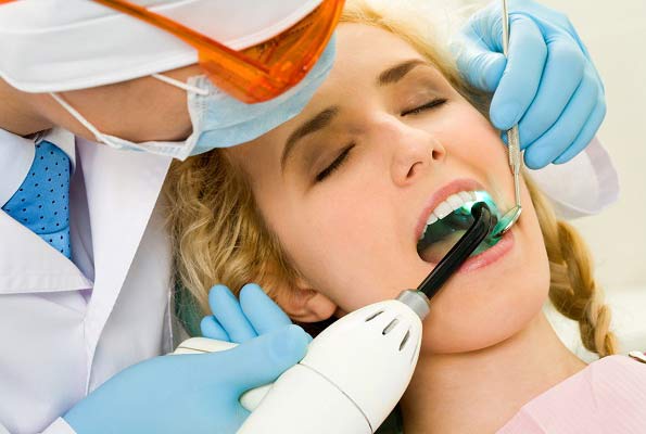 patient with mouth open having light applied to teeth to solidify filling
