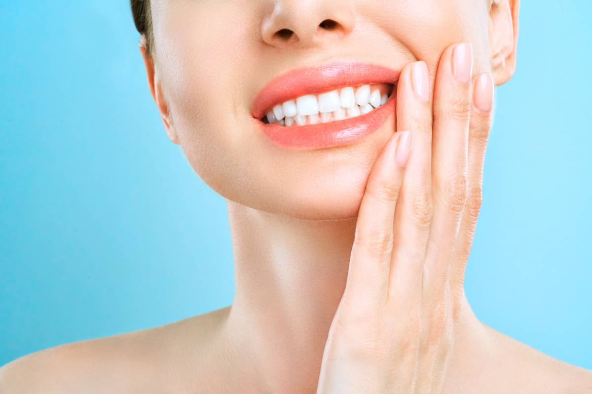 woman with pained expression massaging side of mouth