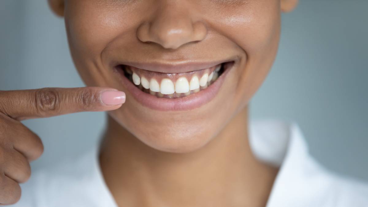 Woman smiling because she avoided the causes of inflamed gums.